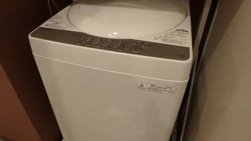 A front view of a white washing machine with a control panel and a safety warning label.
