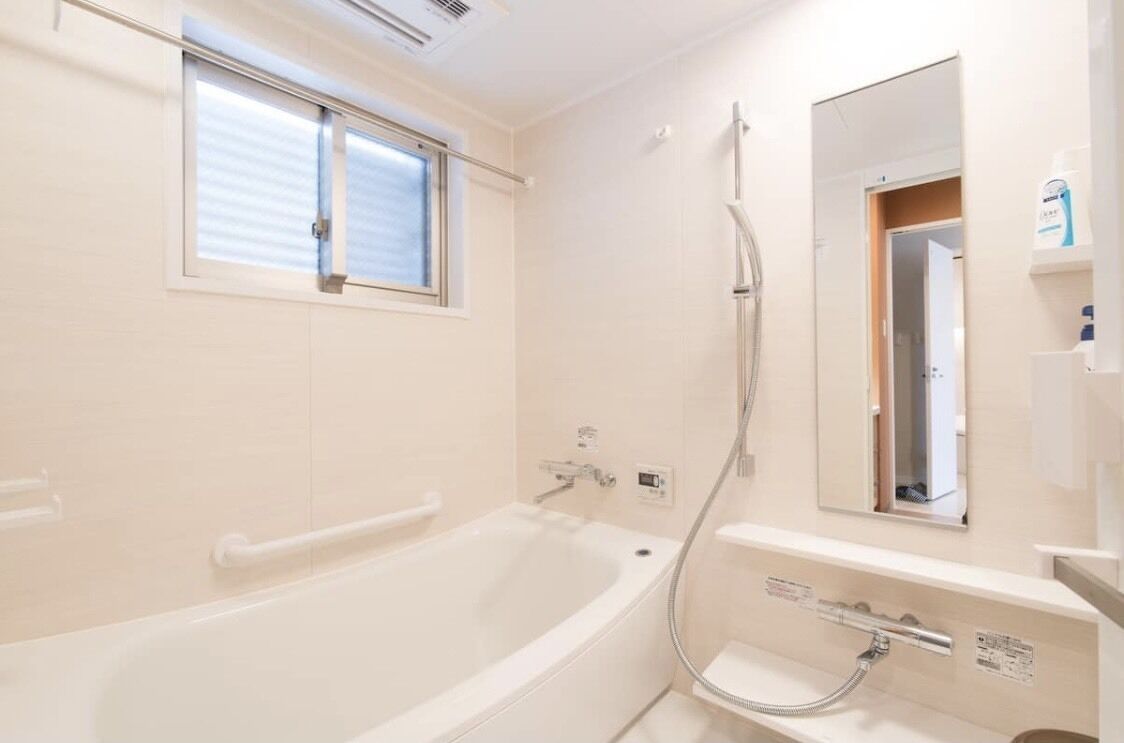 A modern bathroom with a bathtub, a shower, and a mirror.