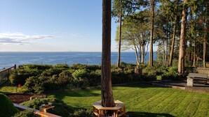 A landscaped garden with a bench and a picnic table, overlooking a body of water.