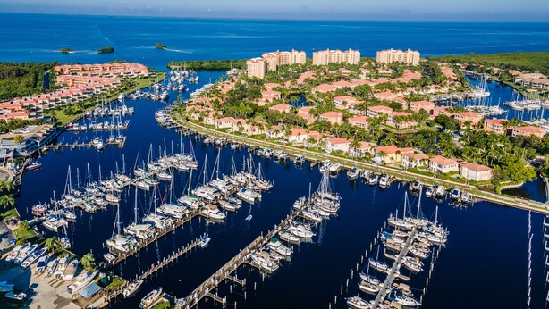 An aerial view of a marina with numerous boats docked, surrounded by residential buildings and lush greenery. - Your Waterfront Retreat at Burnt Store Marina (Punta Gorda)