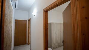 A hallway with wooden doors, a white air conditioning unit, and a light fixture on the ceiling.