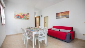 A dining area with a table set for four, a red sofa, and two wall art pieces.