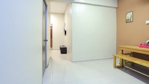 A hallway with a wooden bench, a white door, and a small black box on the floor. - OYO HOME 90244 Dkeris 2bhk Apartment (Malacca City)