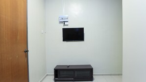 A room with a wooden door, a white wall, a mounted television, and a black entertainment unit. - OYO HOME 90244 Dkeris 2bhk Apartment (Malacca City)