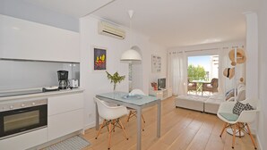 A modern kitchen with a dining area, a sofa, and a view of the outdoors. - Alcúdia Sea - Modern apartment on the seafront in Alcúdia, Mallorca (Alcúdia)
