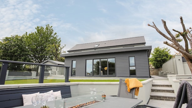 Un patio moderno al aire libre con una mesa de vidrio, asientos y una chimenea.