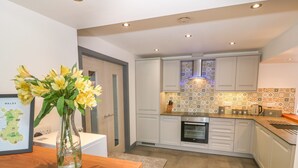 Una cocina moderna con armarios blancos, encimera de madera y salpicadero azulejado.