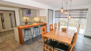 Una cocina moderna con una isla central, taburetes de bar y un comedor con mesa y sillas de madera.