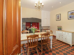Ein Essbereich mit Holztisch, vier Stühlen, einem Blumenstrauß, einer Chandelierleuchtre, einem weißen Schrank und einem Schachbrettfußboden.