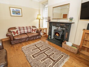 Ein gemütliches Wohnzimmer mit einer Ledersofa, einem Kamin, einem Teppich und Holzboden.