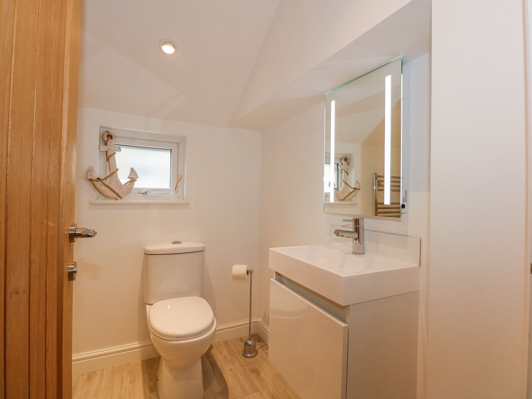 A small, modern bathroom with a toilet, sink, and mirror.