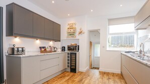 A modern kitchen with grey cabinets, wooden flooring, and a built-in microwave.