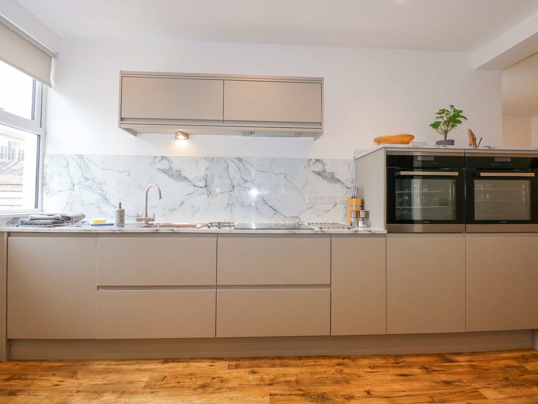 Een moderne keuken met marmeren aanrechtbladen, roestvrijstalen apparatuur en een houten vloer.