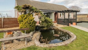 A house with a garden, a pond, and a wooden deck. - The Croft Bungalow (Wigton)
