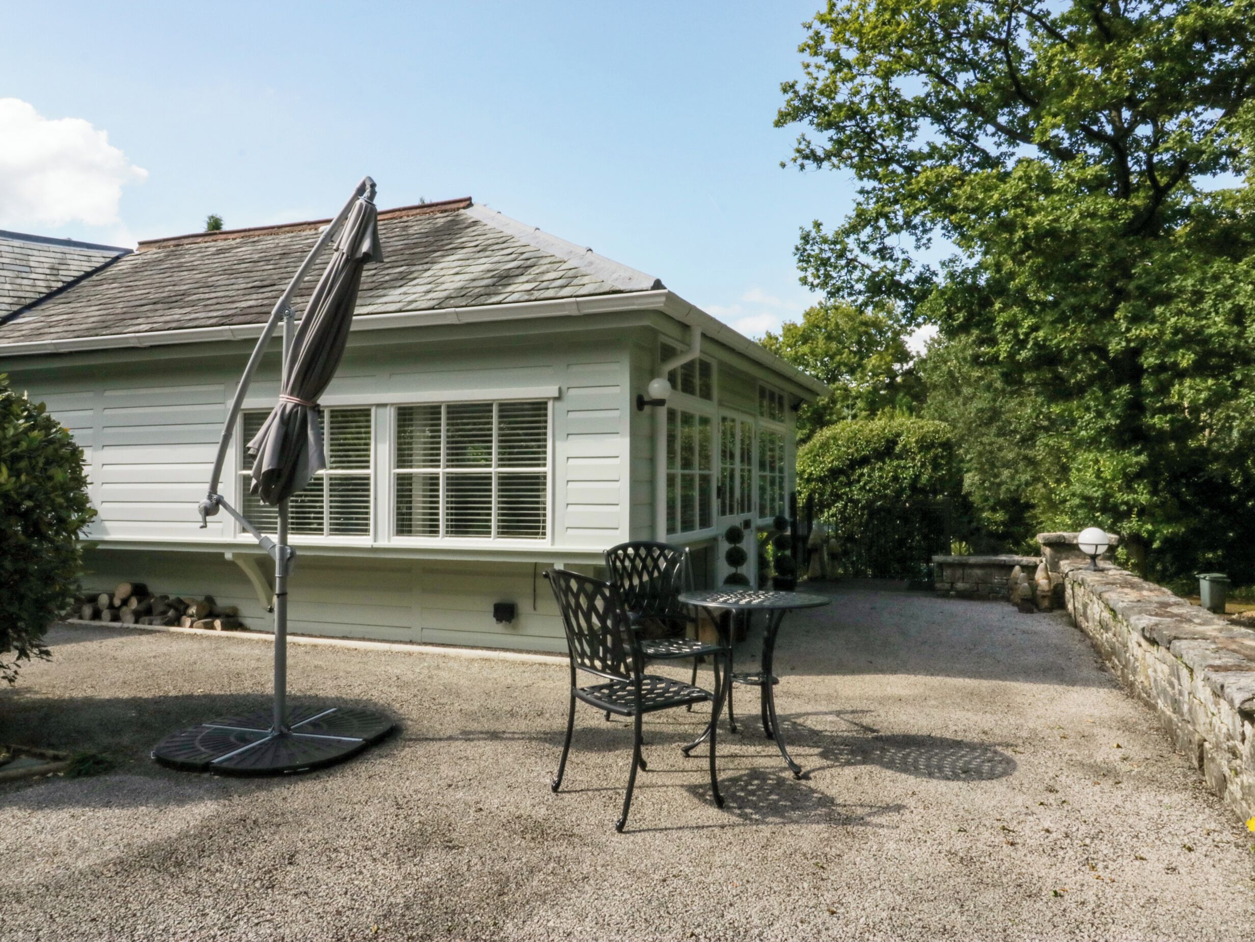 Een huis met een overdekte patio, een grindpad en een stenen muur.
