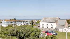 A coastal village with traditional houses, a church, and parked vehicles. - Eloen (Newquay)