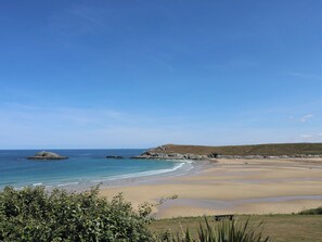 Une plage avec un ciel dégagé, une eau calme et des collines qui se dessinent à l’horizon.