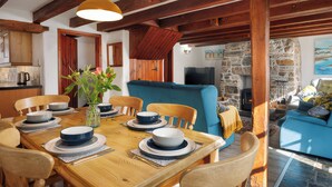 Ein Essbereich mit einem Holztisch, gedeckt für vier Personen, einer Blumenvase und einem blauen Sofa im Hintergrund.