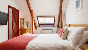 Ein Schlafzimmer mit einem Bett, einem Fenster, einem Fernseher und einer Holztür.