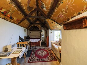 A cozy room with a wooden ceiling, a bed, a desk, and a chair. - Toad Hall Cottage (Totnes)