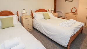 Ein Hotelzimmer mit zwei Einzelbetten, jeweils mit Holz Kopfteilen, weißer Bettwäsche und einem grünen Kopfkissen. An den Nachttischen stehen Lampen, ein Spiegel und ein gerahmtes Bild an der Wand.