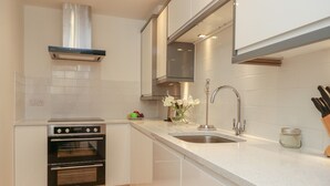 Une cuisine moderne avec des meubles blancs, des appareils en acier inoxydable et un plancher en bois.