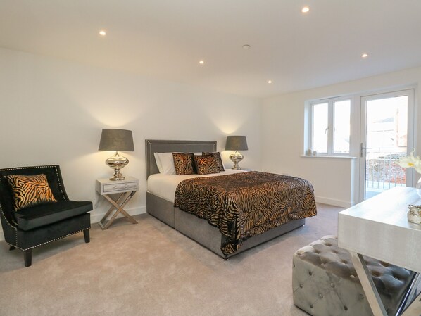 A bedroom with a bed, two bedside tables with lamps, a chair, a bench, and a window with a view.