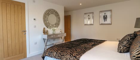 A bedroom with a bed, a dresser, a mirror, and two framed pictures on the wall.