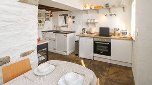 Une cuisine compacte avec des meubles blancs, un lave-vaisselle Bosch, un évier et un plan de travail sur lequel se trouve un grille-pain.