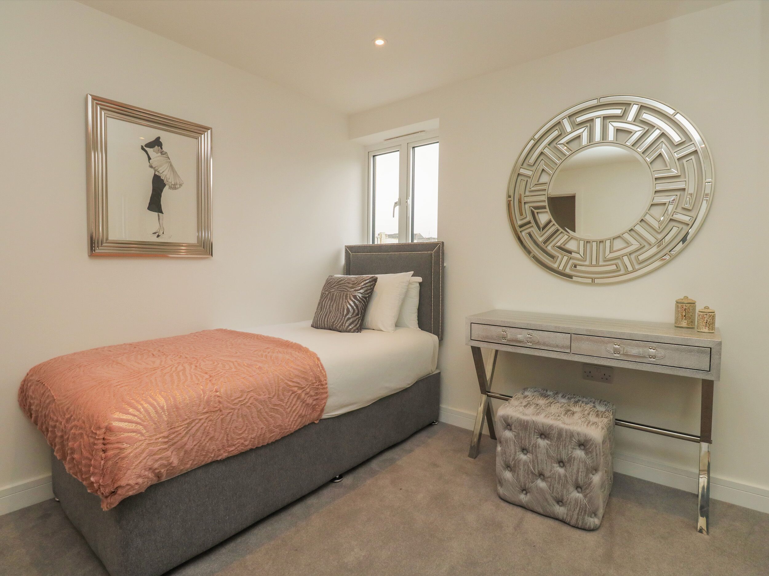 A bedroom with a bed, a dresser, a mirror, and a framed picture on the wall.