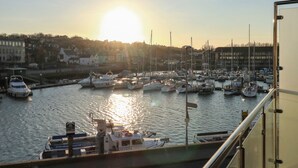 A marina with boats docked, a clear sky, and buildings in the background. - Harbourside Haven Apartment 4 (Weymouth)