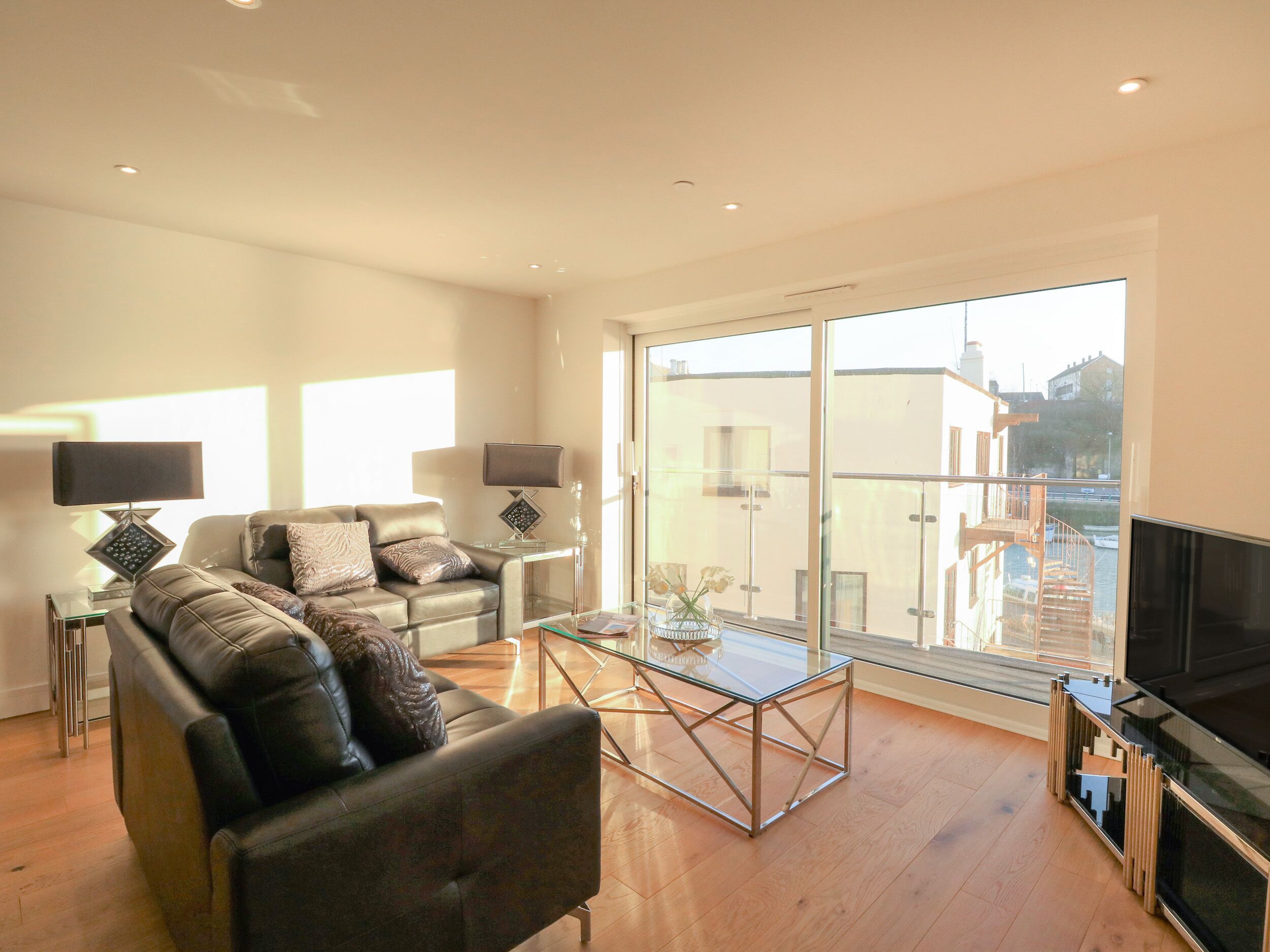 A modern living room with a leather sofa, a glass coffee table, and a flat-screen TV.