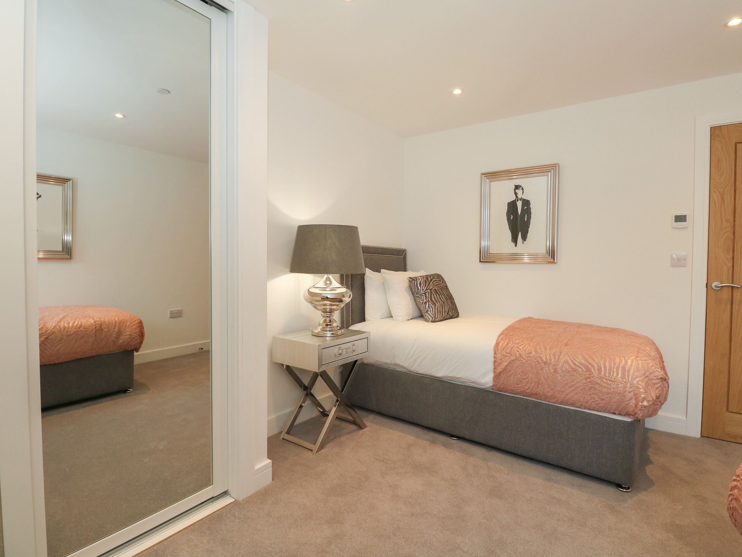 A bedroom with a bed, bedside table, lamp, and a framed picture on the wall.