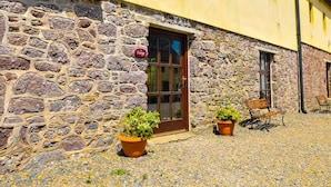 A stone building with a yellow facade, a wooden door, and two potted plants. - The Barn (Fethard on Sea)