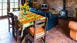 A rustic interior with a stone wall, a fireplace, a sofa, and a dining table with chairs. - The Barn (Fethard on Sea)