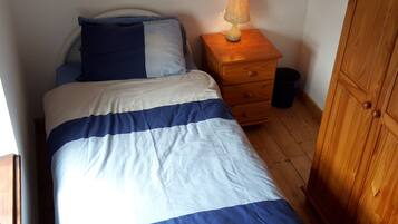 A bedroom with a bed, a bedside lamp, a wooden nightstand, and a wardrobe.