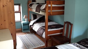 A bunk bed room with a wooden headboard, a bedside table with a lamp, and a window. - The Barn (Fethard on Sea)