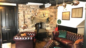 A cozy room with a stone fireplace, leather sofas, and a sign indicating a flea market. - Heather (Ruthin)