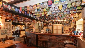 A bar with a brick counter and stools, surrounded by walls adorned with beer labels. - Heather (Ruthin)