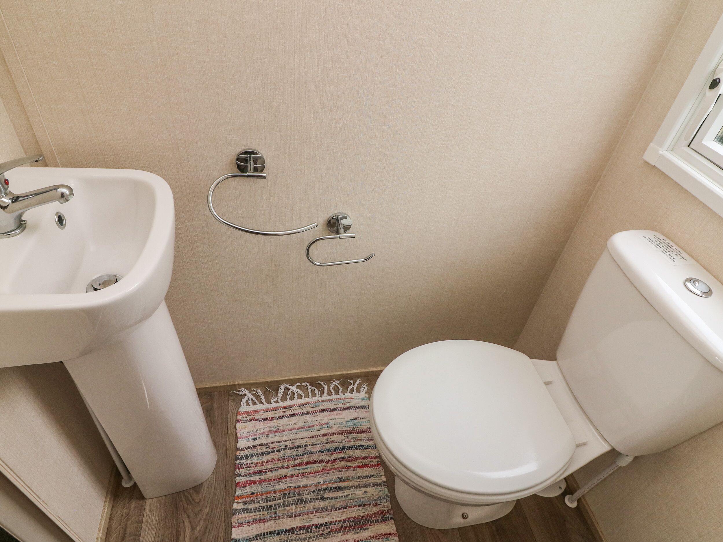 A small bathroom with a white sink, toilet, and a small window.