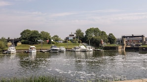 A river with boats docked, a bridge, and a marina. - The Coach House Apartment (Tewkesbury)