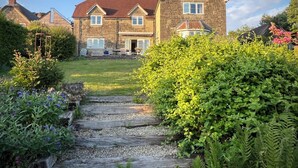 A stone house with a red roof, a front porch, and a gravel pathway leading to the entrance. - Samstone (Shaftesbury)