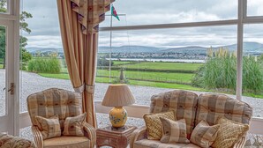 A room with two armchairs facing a large window overlooking a rural landscape. - Tal Gwynedd (Llanfairpwllgwyngyll)