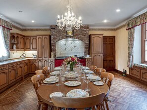 A dining room with a large wooden table set for six, surrounded by wooden chairs.