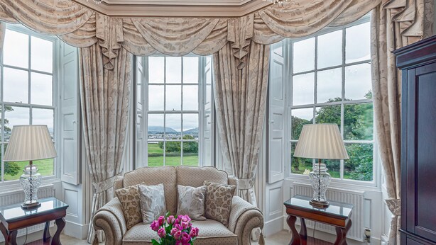 A spacious room with a large window, a sofa, a coffee table, and a lamp. - Tal Gwynedd (Llanfairpwllgwyngyll)
