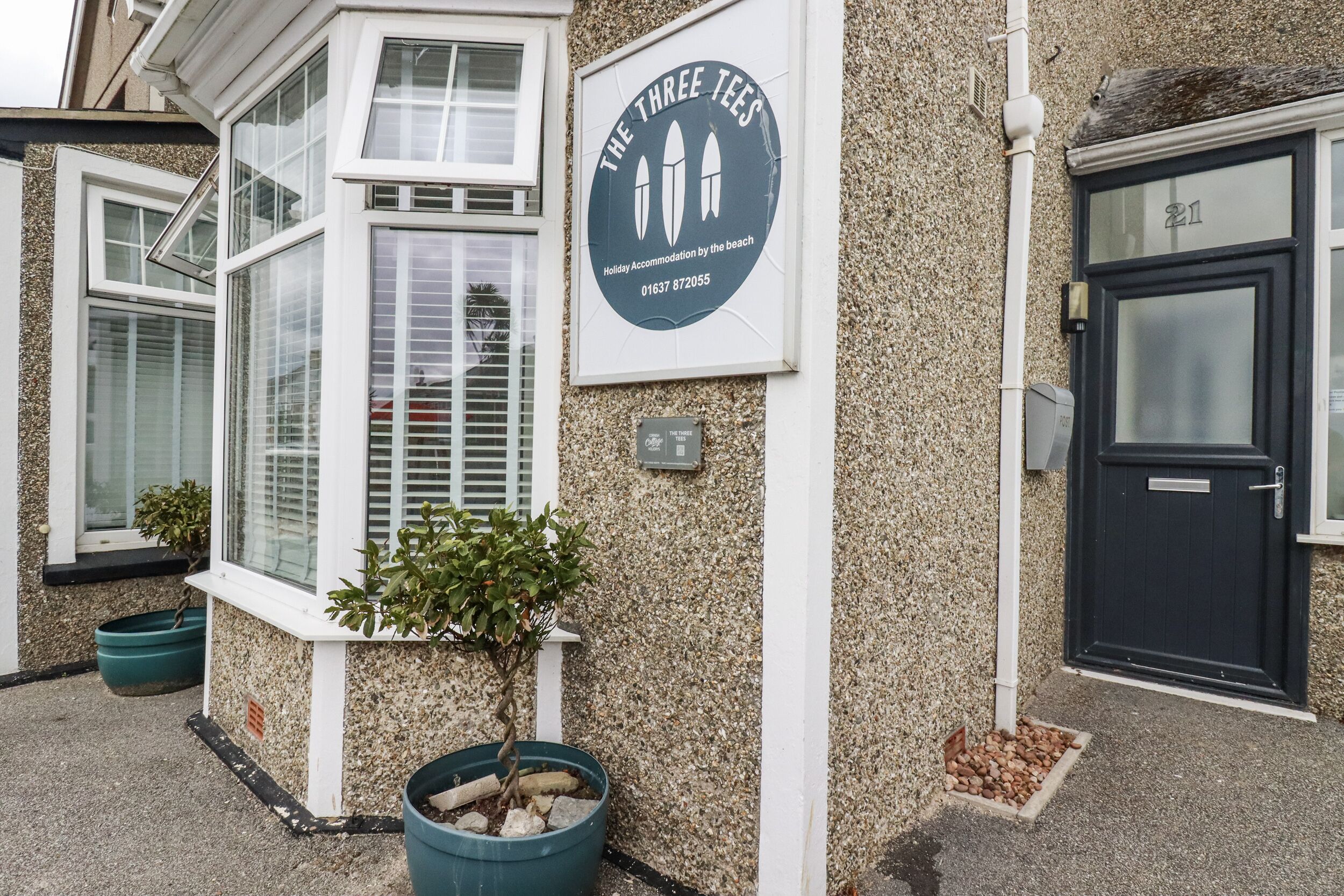 A building with a sign that reads "The Three Tees" and a contact number.