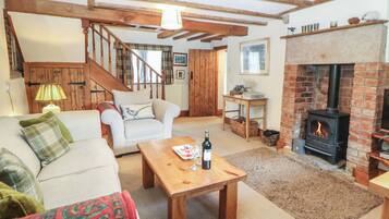 Una sala de estar acogedora con chimenea, un sofá, una mesita de centro y una escalera que sube a otra habitación.