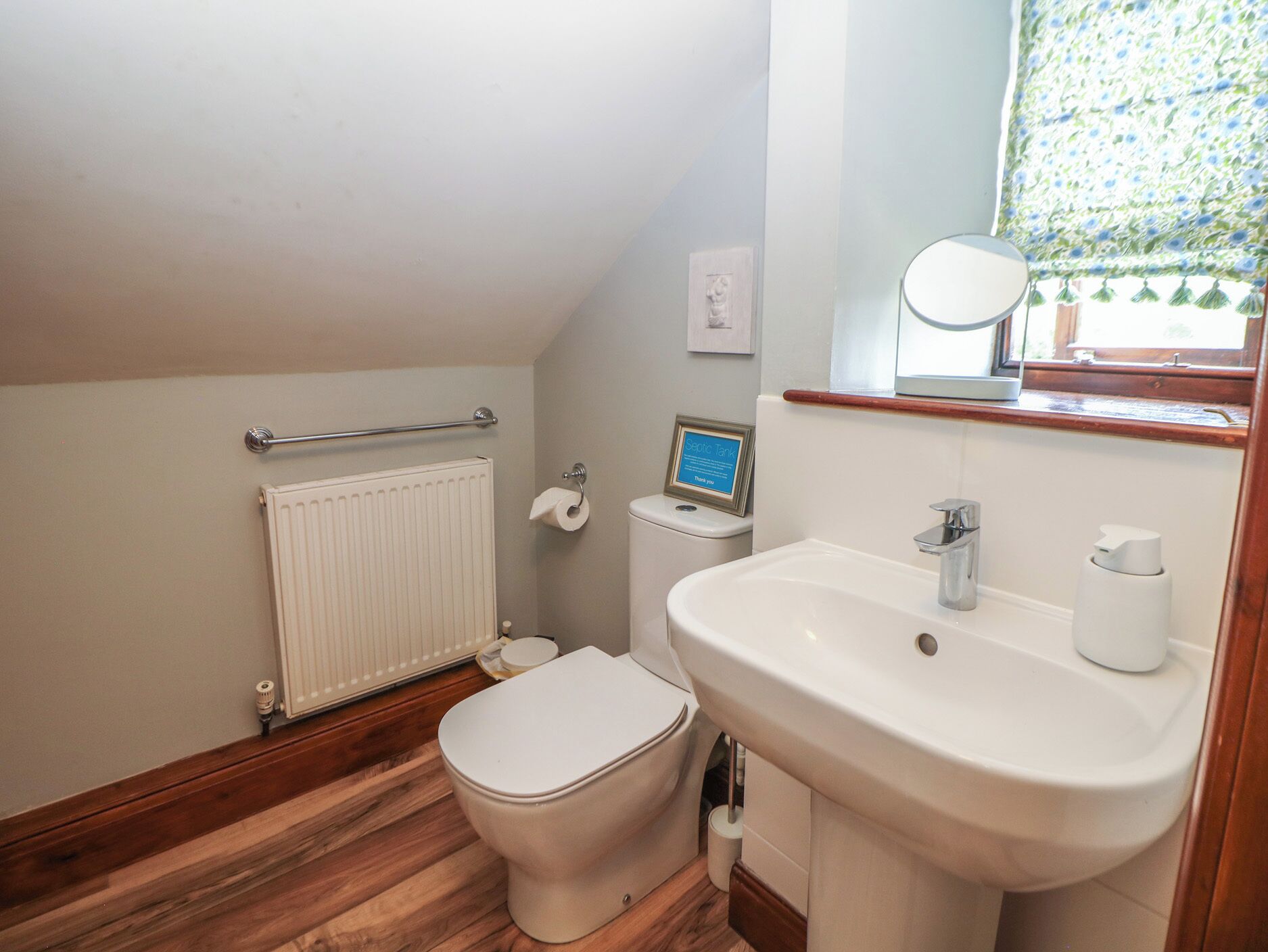 A small, compact bathroom with a toilet, sink, and radiator.