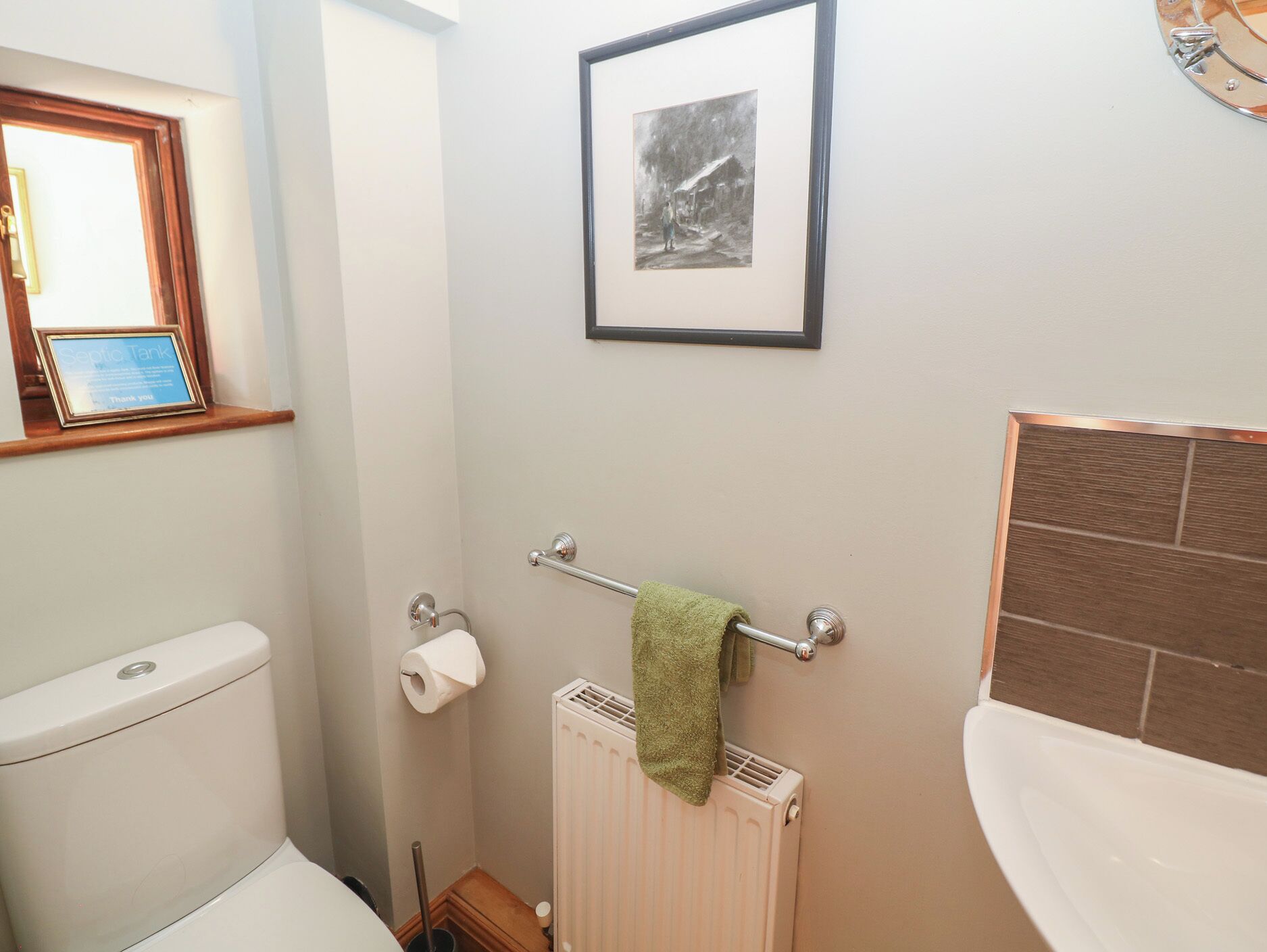 Un baño con inodoro, toallero con toalla, un cuadro en la pared y un radiador.