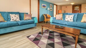 Una sala de estar con dos sofás azules, una mesa de centro de madera y una alfombra estampada.